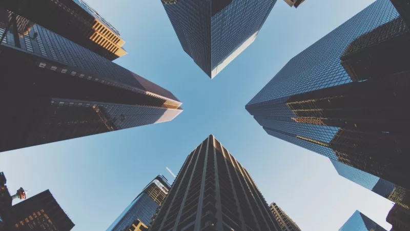 Low angle view of skyscraper roofs under a blue sky, capturing the essence of urban architecture.