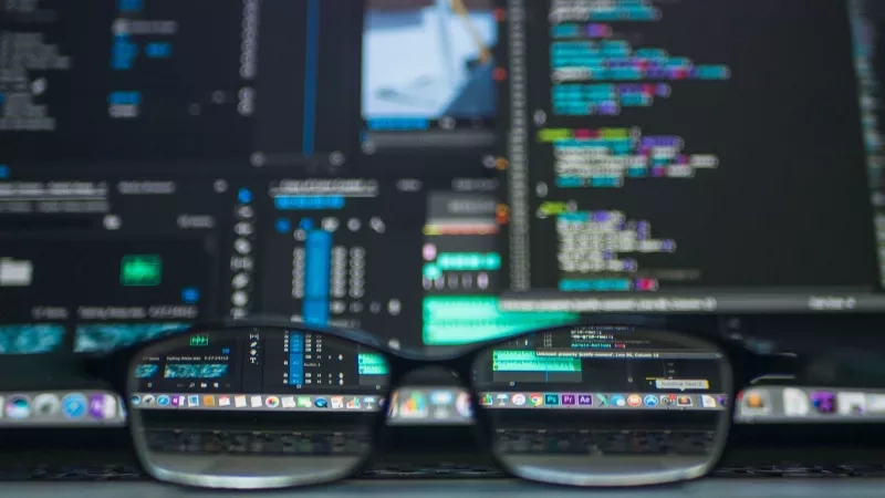 Glasses over a computer keyboard with a computer screen in the background that is out of focus.