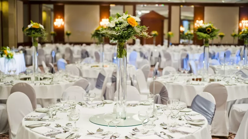 Set banquet tables at the Grand Hyatt Singapore with floral centerpieces and cutlery on the table.