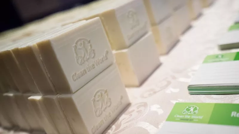 Several white soap bars that say "clean the world" and some business cards on the table.