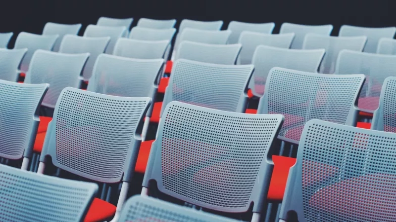 A conference hall with gray chairs and red seats arranged in rows.
