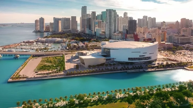 An aerial view of a cityscape with high-rise buildings, a harbor, and lush greenery.