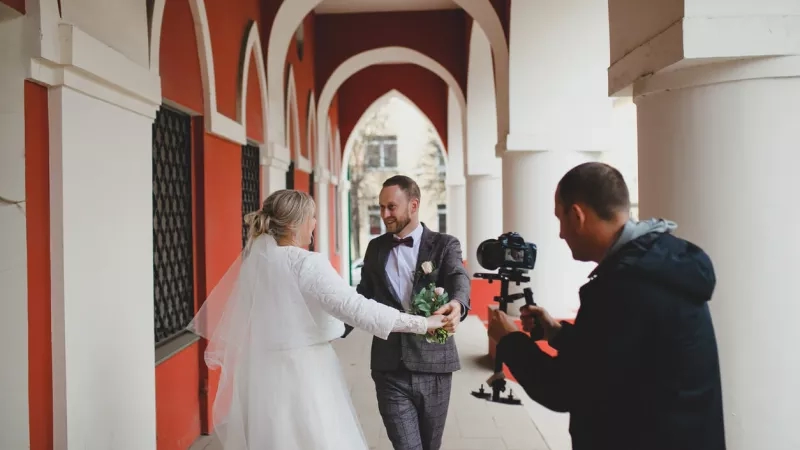 Videographer recording couple for wedding venue marketing materials in a bright and elegant space.