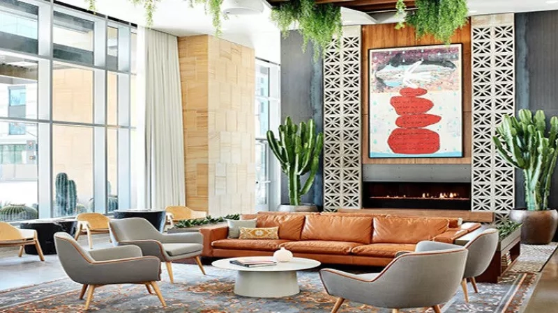 Hotel lobby with large windows, a fireplace, and comfortable seating, showcasing a blend of modern and rustic decor.