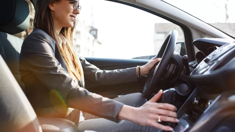 Businesswoman driving a car to a meeting with a cup of coffee in her cup holder.