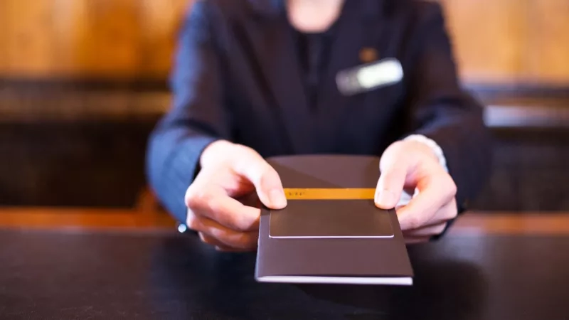 Employee at the hotel front desk handing over a credit card to a customer