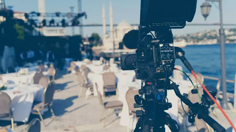 Video camera set up for a hybrid wedding on the waterfront with beautiful architecture in the background.