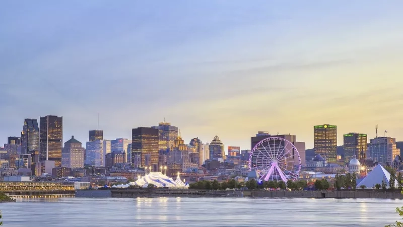 Montreal skyline at dusk with Ferris wheel, a tent, and a pyramid in the foreground.