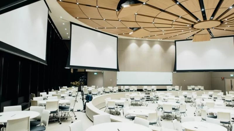 Modern conference room with spaced seating, circular layout, and large screens for presentations or meetings.