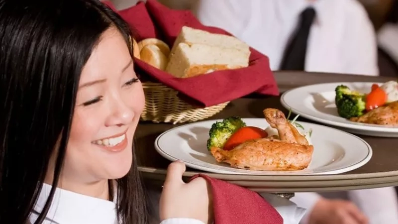 Smiling server holding a tray of delicious food in the hospitality industry at the Omni Grove Park Inn.
