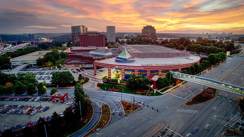 An aerial view of the Cvent Headquarters with cars, trees, and a sunset sky in the background.