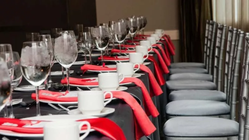 A table is set with plates, wine glasses, and napkins for a formal event at the hotel.
