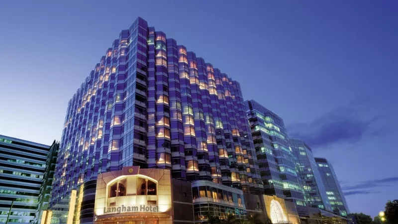 Langham Hotel exterior at night, showcasing modern architecture and a vibrant cityscape ambiance.