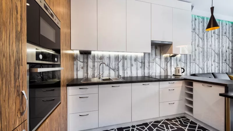 Modern kitchen at extended stay hotel with wooden cabinets, white countertops, and geometric rug.