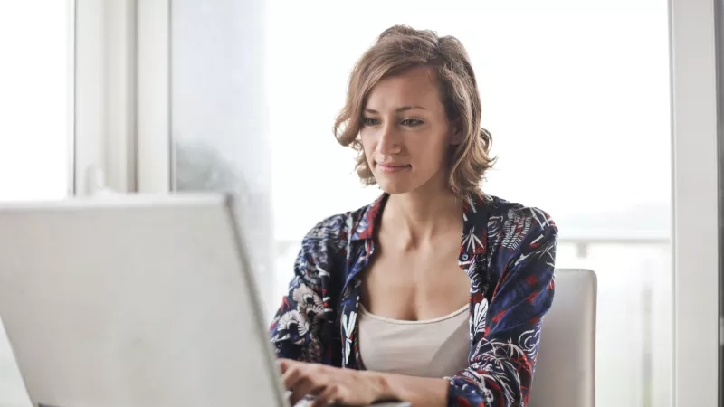 Woman sitting at a table working on her laptop for a virtual fundraising event.