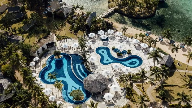 Aerial view of Warwick Fiji resort with pool, beach, and lush landscaping.