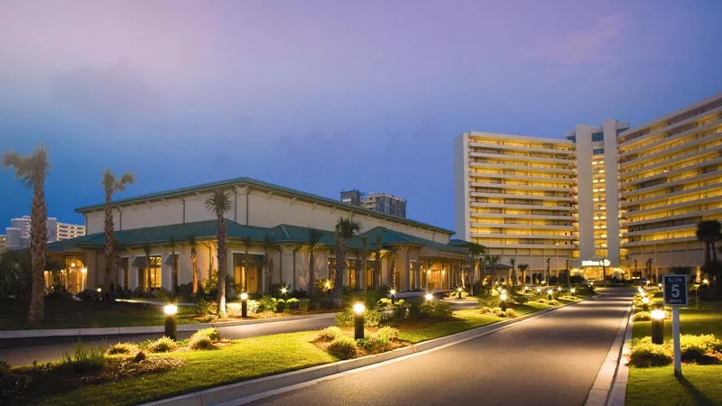 A building with a green roof, a road, and a signboard with the text "5" in the dusk.