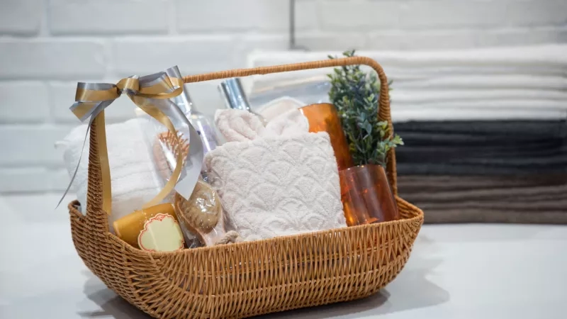 Hotel welcome basket with gifts for guests including towels, candles, and a potted plant.