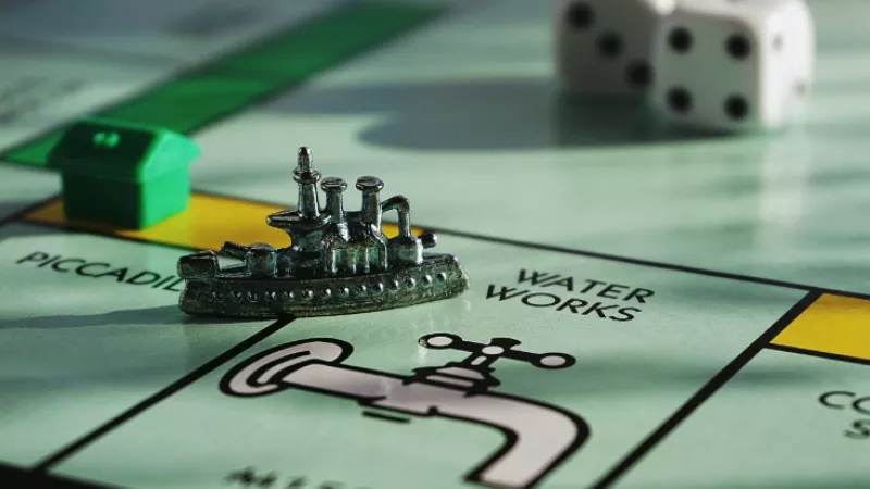 A boat toy is on a game board with a waterworks illustration and two dice on top.