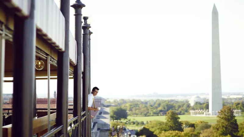 POV at the W Hotel, a man in a white shirt and tie looking out the window.