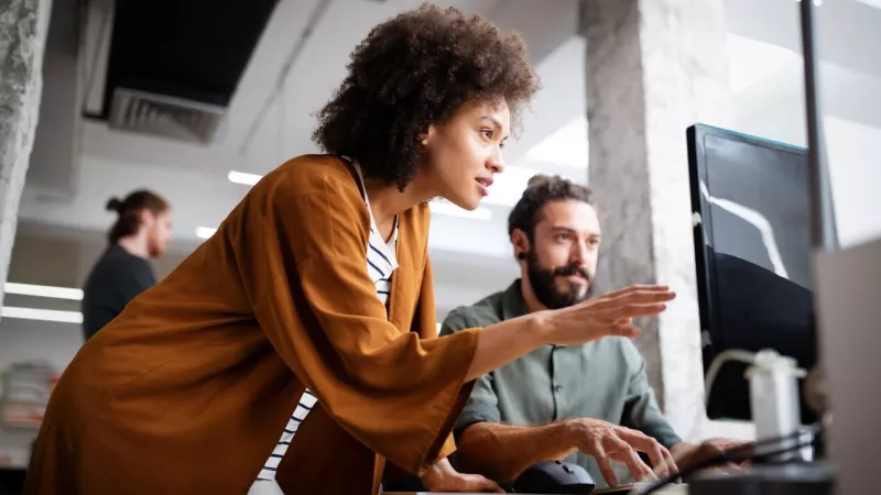 Digital marketing team working on a computer with a mouse in a modern office environment.