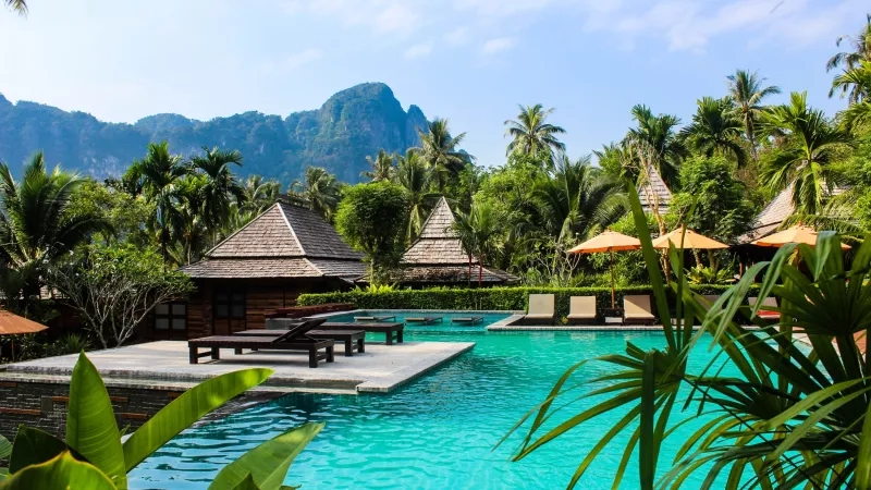 Tropical pool area with lush landscaping, wooden cabanas, and serene mountain views at Khao Sok National Park.