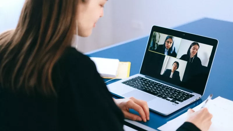 A woman is on a video call with three other people on her laptop.