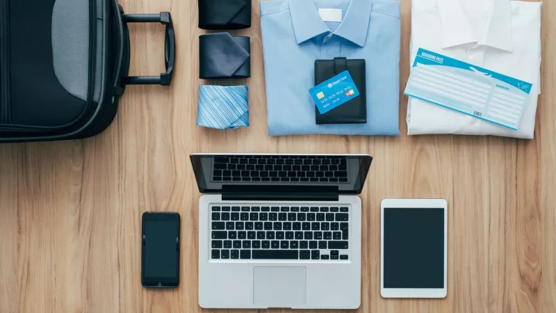 Business travel essentials laid out on table for business trip.