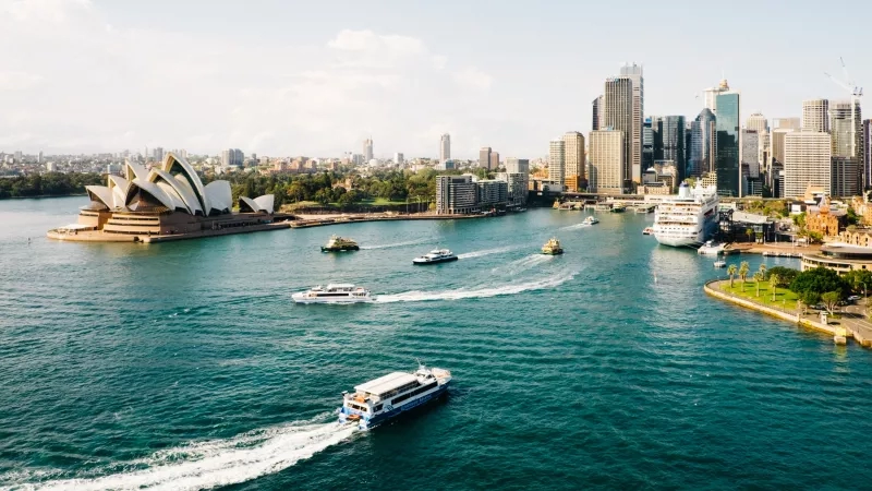 Sydney Harbour with the Opera House, cruise ship, and boats, with a cityscape in the background.