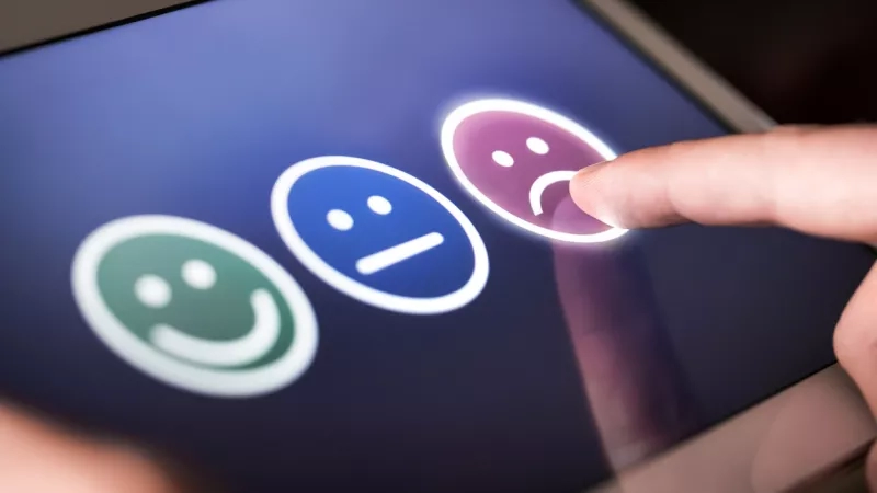 Person using a tablet and pressing on an emoji to show their feelings about a topic.
