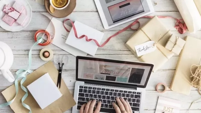 A laptop is placed on a desk with different gift boxes and other objects on it.