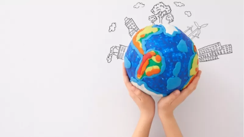 Hands holding a clay globe with a backdrop of illustrations and text depicting a sustainable city.