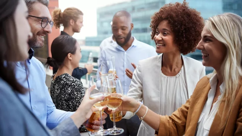 Group of people toasting with drinks during happy hour after work at The Office NYC.