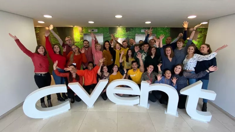 Group of people posing in front of a sign with the word "cvent" in a lobby.