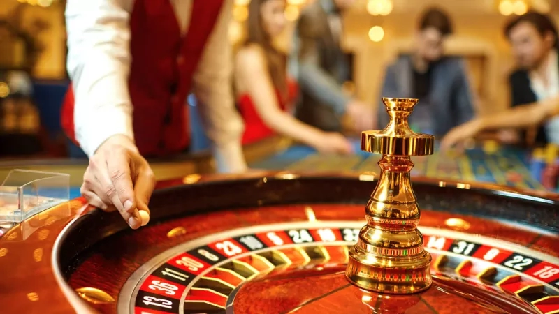 A casino roulette table with a croupier spinning the wheel and customers placing bets.