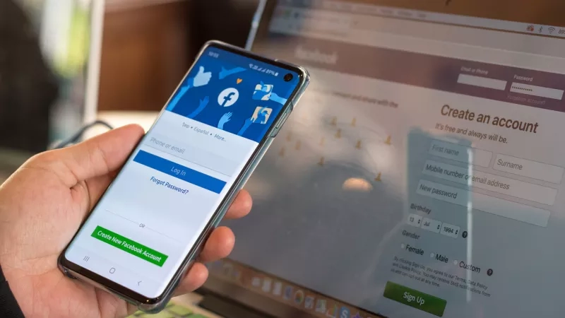 Person signing in to Facebook on phone and computer