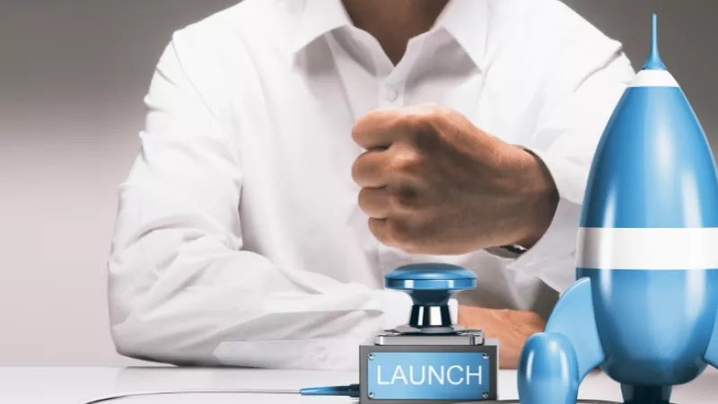 A man is sitting at a desk ready to launch a product with a rocket.