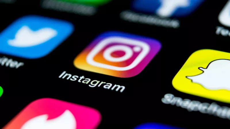 A close-up of the Instagram logo on an iPhone with other social media apps.