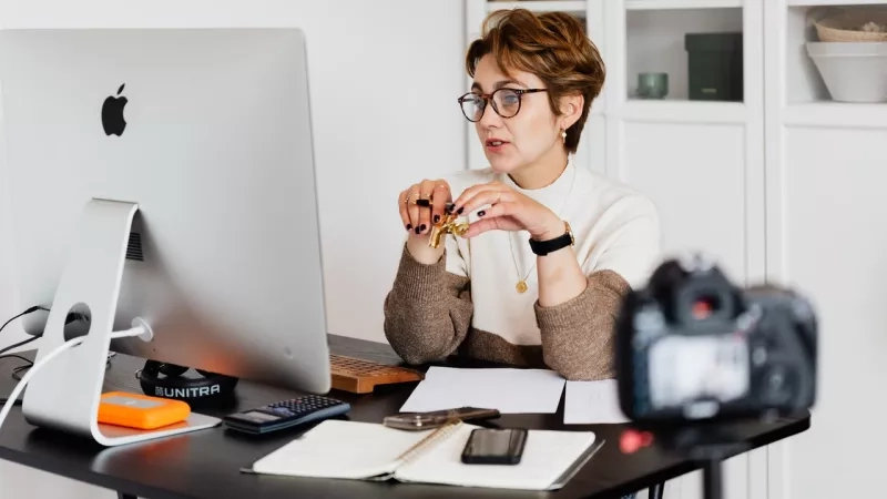 A woman sits at her desk recording a video, holding up a bunch of keys.