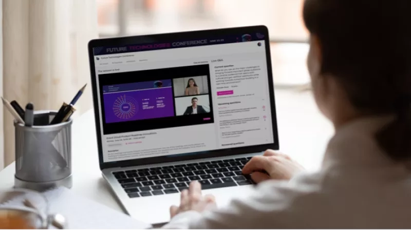 Woman working on laptop showing Future Technologies Conference 2023 webpage with live Q&A section visible.