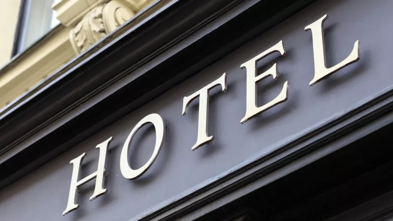 Gold sign on exterior of hotel with the word hotel on it.
