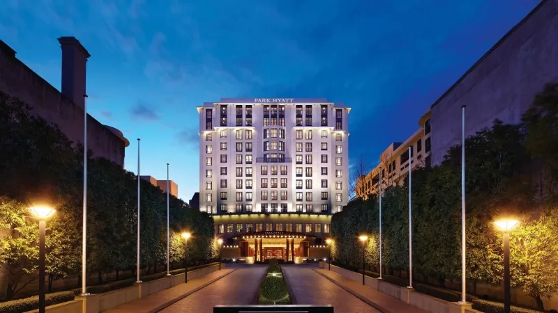Park Hyatt Melbourne exterior view at dusk with a wide driveway and lit streetlights on both sides.