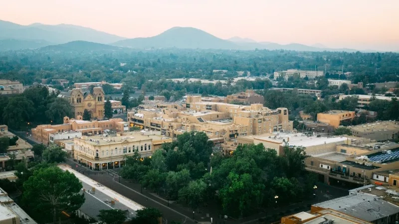 A top view of Santa Fe, New Mexico, with a mountain range in the background at sunset.