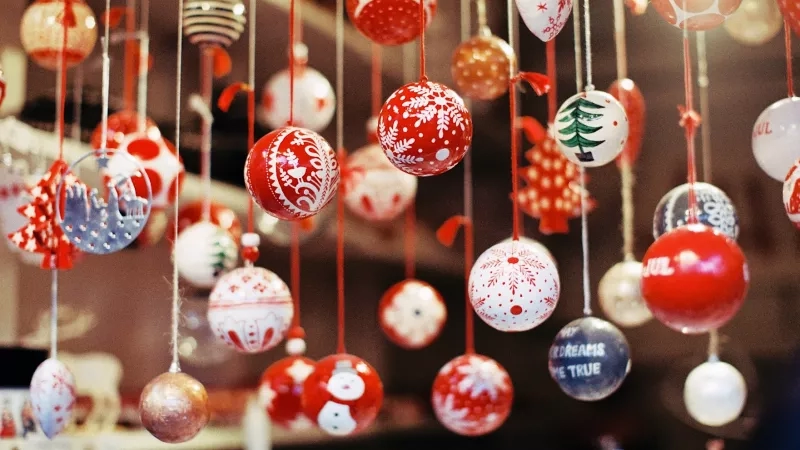 Several Christmas balls with text and illustrations hanging from the ceiling at the Christmas market in Brussels.