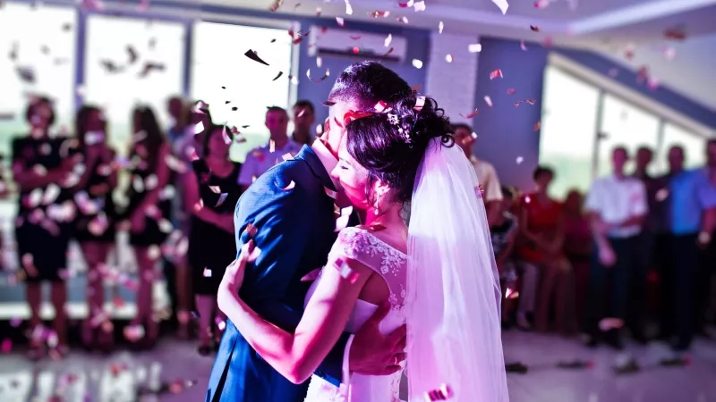 Couple dancing at wedding with purple lights and confetti at the reception of the wedding.