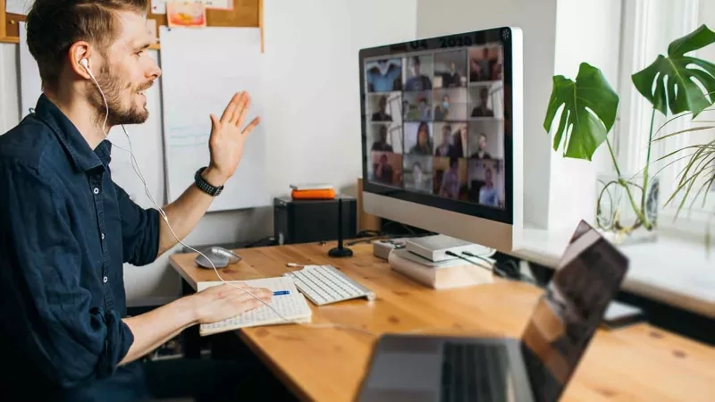 Man with headphones and laptop participating in a virtual meeting with proper etiquette.