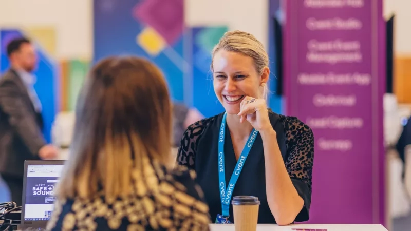 Woman with badge smiling while speaking to another woman at a Meet Safe + Sound event.