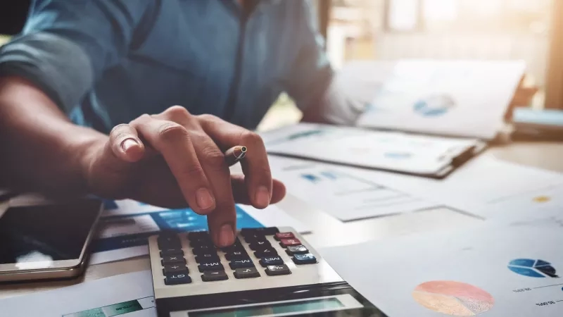 Hotel manager using calculator and spreadsheets for hotel budgeting.