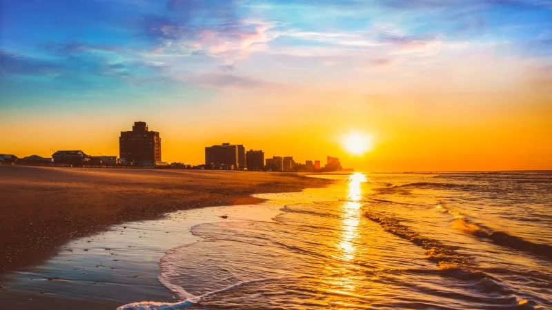 Golden sunset over the beach and city skyline in the distance.