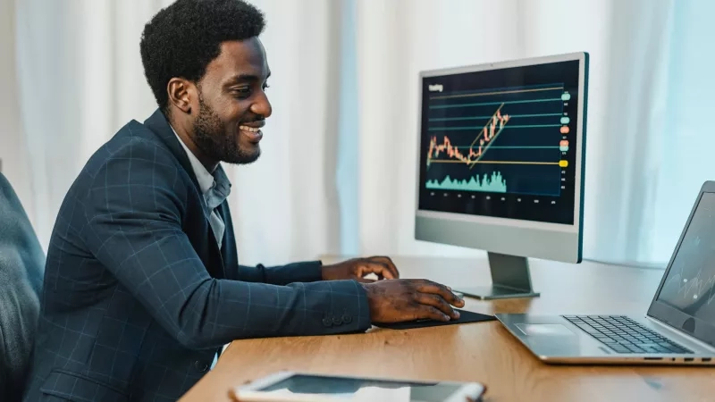A man smiles while viewing a positive growth chart on his computer in 2022.